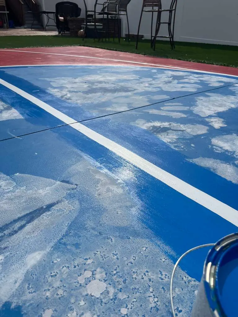 Before backyard sport court repaint showing worn blue surface